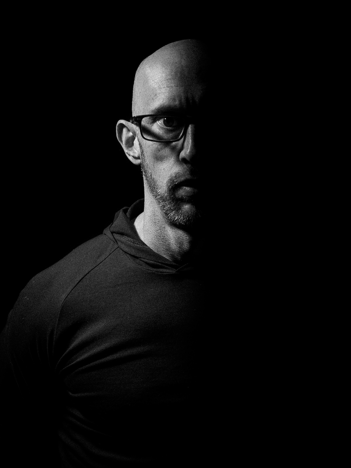 Paul Lewis, half lit against a black background